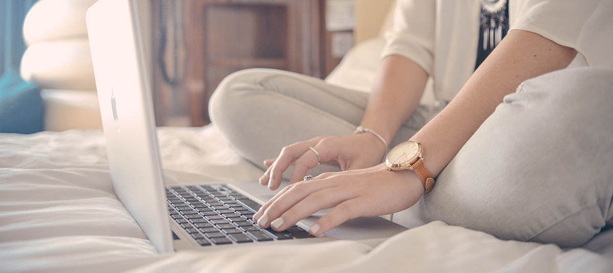 Person sitting on bed typing on computer