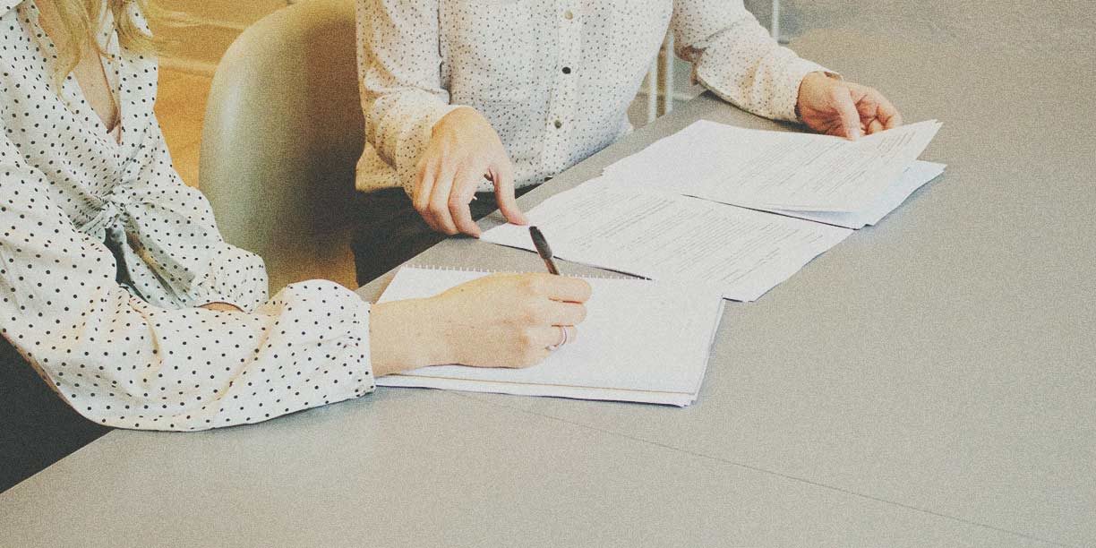 Two people signing a set of paper forms