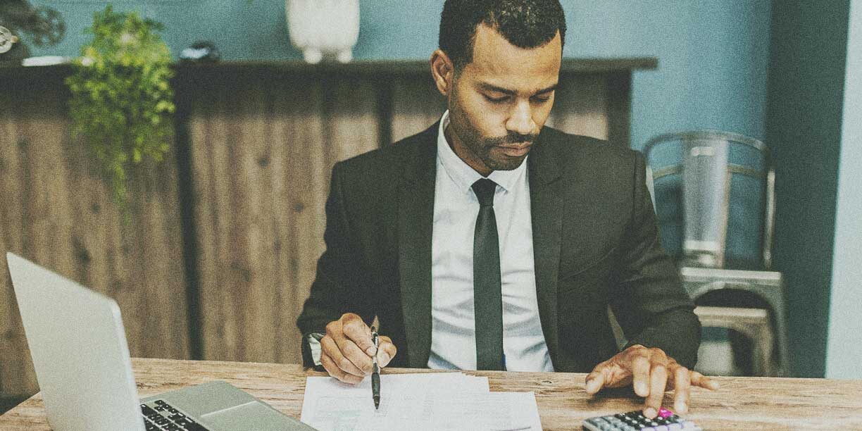 Man in suit filling out a nonprofit audit form at his desk