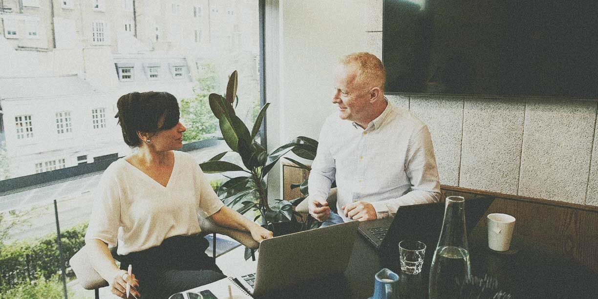 Woman in white meeting with a man in gray in a conference room