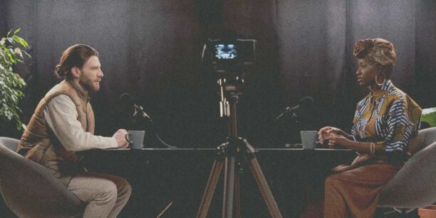 Man and woman sitting in a podcast studio recording a podcast