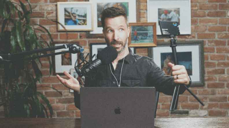 man in black filming himself with a camera