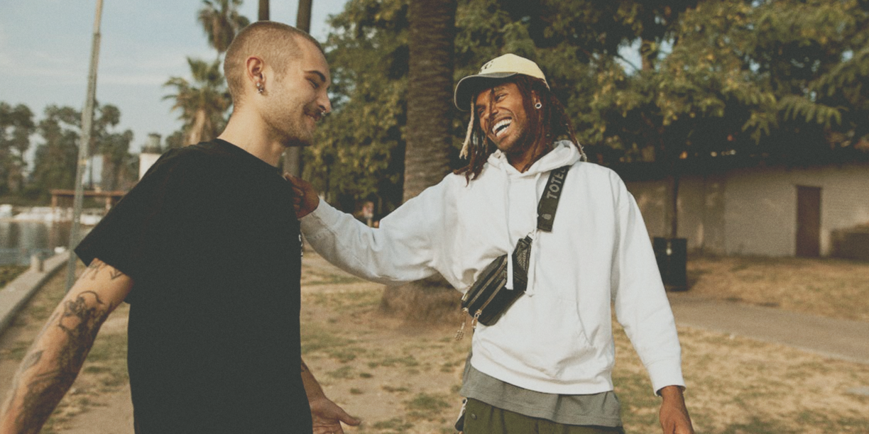 Man in white sweatshirt patting a man in black tshirt on the back