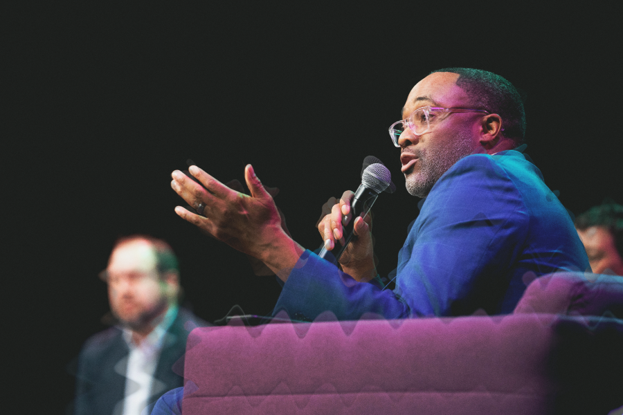 Man in blue jacket speaking into a microphone at Collaborative