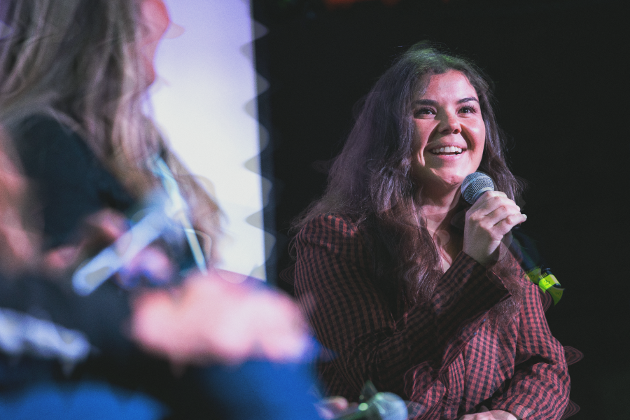 Woman in purple speaking into a microphone